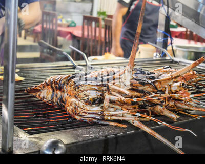 Gegrillter Hummer auf einem Rost über das Feuer im Seafood Night Market, gegrillte Garnelen und Hummer auf dem Grill am Nachtmarkt in Hua Hin, Thailand Stockfoto