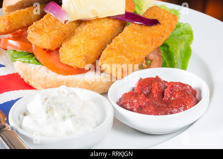 Die typisch englischen Mittagssnack von Fischstäbchen in einem Brötchen mit Ketchup und Zahnstein. Stockfoto