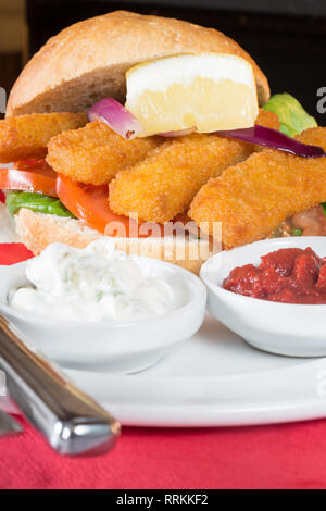 Die typisch englischen Mittagssnack von Fischstäbchen in einem Brötchen mit Ketchup und Zahnstein. Stockfoto