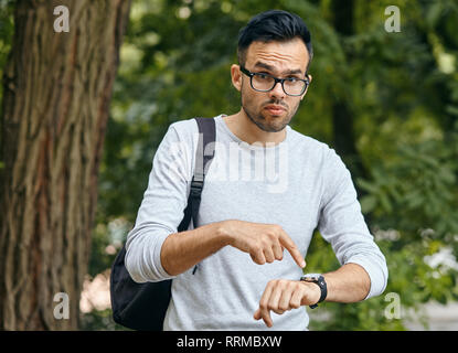 Junge Unternehmer verweist auf seine Armbanduhr am Arm. Stockfoto