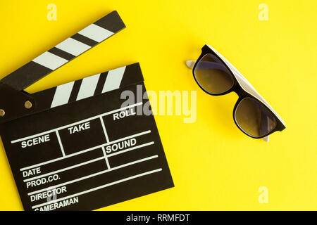 Kino und Film, Hintergrund. Klappe und 3D-Brille auf gelbem Hintergrund minimal kreatives Konzept isoliert. Stockfoto