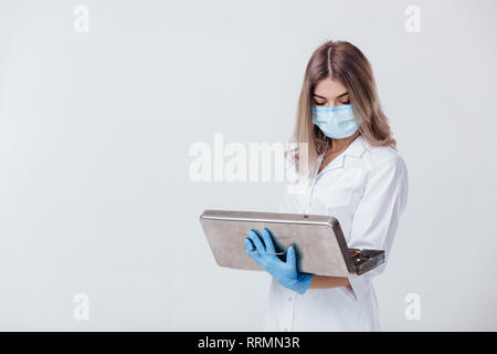 Portrait von Frau Doktor mit Gesichtsmaske und medizinische Handschuhe hält einen Beutel mit medizinischen Instrumenten aus Metall Stockfoto