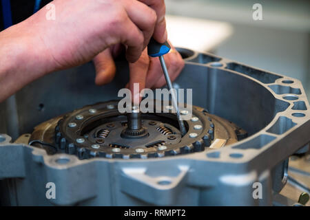 Reparatur der Mensch zur Festsetzung auto Teil mit Screw Driver. Junge Mechaniker in seiner Werkstatt zur Festsetzung ein Auto Stockfoto