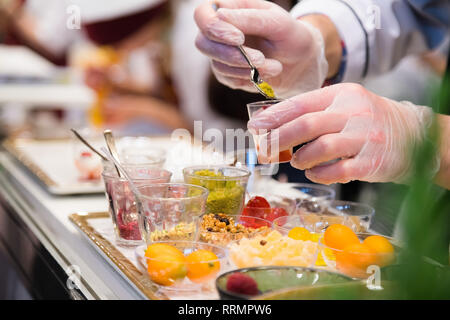Koch tragen weiße Handschuhe und hinter Mittagessen Service Station mit Sortiment von Lebensmitteln Stockfoto