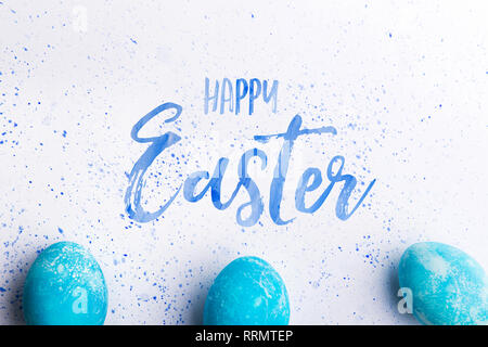 Frohe Ostern Phrase und farbigen blaue Eier auf einem weißen Hintergrund. Studio gedreht. Flach. Stockfoto