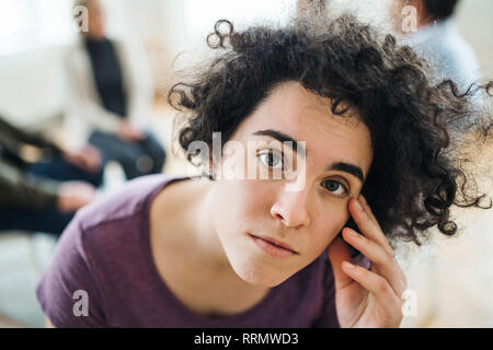 Ein Porträt der jungen attraktiven gedrückt Frau während der gruppentherapie. Stockfoto