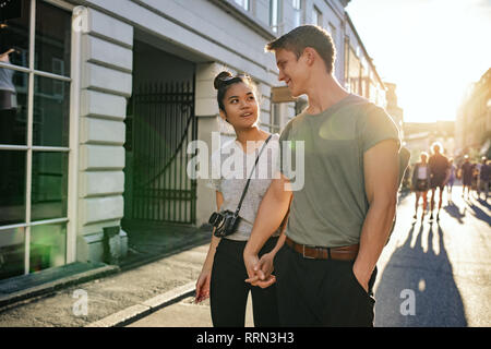 Lächelnde junge Paar erkunden Straßen der Stadt zusammen zu Fuß Stockfoto