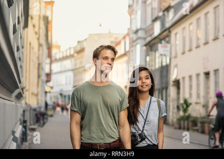 Lächelnden jungen Paar hält Hände beim Gehen in der Stadt Stockfoto