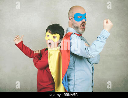 Vatertag, Vater und Sohn, gekleidet wie ein Superheld gegen grauer Hintergrund Stockfoto