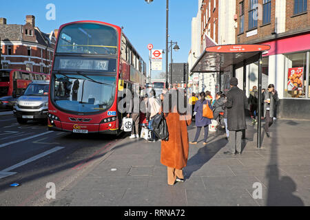 Leute, die auf einer 432 Bus und Passagiere warten an einer Bushaltestelle in Brixton Road in Brixton London SW9 England UK KATHY DEWITT Stockfoto