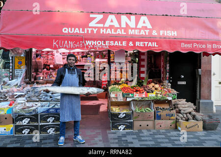 Brixton street scene Trader Holding barracuda Fische außerhalb Zana Halal Fleisch & Fisch store Electric Avenue markt Brixton South London UK KATHY DEWITT Stockfoto