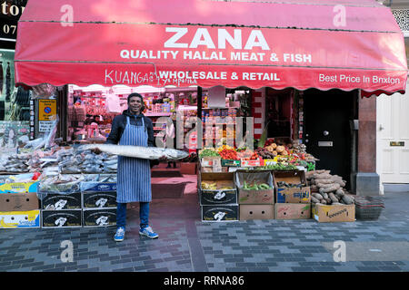 Electric Avenue Brixton Street Market ein Mann Arbeiter Holding barracuda Fische außerhalb Zana Halal Fleisch & Fisch in Süd- London SW9 England UK KATHY DEWITT Stockfoto