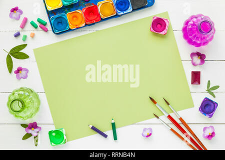 Aquarellfarben, Pinsel für Malerei, rosa violett Blumen und Blatt Papier. Ansicht von oben. Flach. Stockfoto