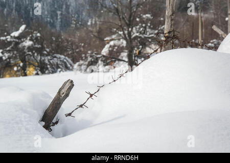 Zaun Details im Schnee in Winterlandschaft - iced Stacheldraht und Holz in verschneite Wiese in der Landschaft Stockfoto