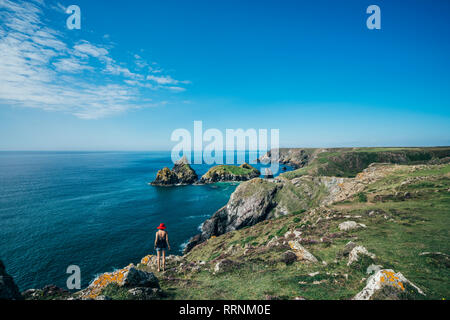 Frau, die an sonnigen Felsen mit Blick auf den Ozean, Cornwall, Großbritannien Stockfoto