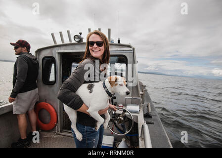 Portrait lächelnde Frau mit Hund an Fischerboot Stockfoto