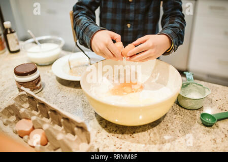 Junge Backen, Rissbildung Ei in die Schüssel in der Küche Stockfoto