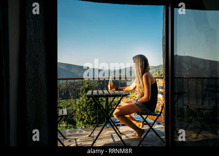 Frau entspannende, trinken Bier auf sonnigen Sommer Balkon Stockfoto