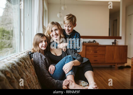 Portrait glückliche Mutter und Kinder kuscheln sich Wohnzimmer Sofa Stockfoto