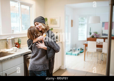 Liebevolle Mutter und Tochter umarmen in der Küche Stockfoto