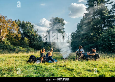 Freunde camping, entspannende um Lagerfeuer in abgelegenen Feld Stockfoto