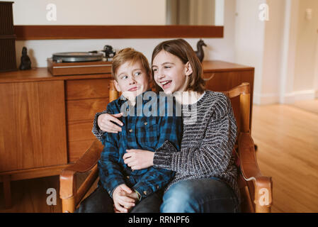 Portrait lachen Schwester umarmen Bruder macht ein Gesicht Stockfoto