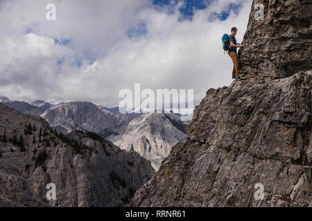 Man Bergsteigen steilen, zerklüfteten Berg Gesicht Stockfoto