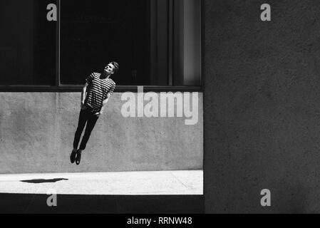 Junger Mann springt auf städtischen Bürgersteig Stockfoto