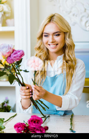 Selektiver Fokus der schönen weiblichen Blumenhändler in Schürze arrangieren Blumenstrauß mit Rosen in Flower Shop Stockfoto