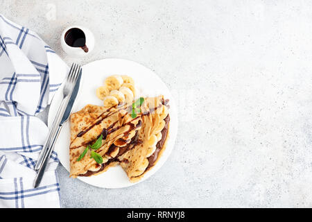 Banane und Haselnuss Schokoladencreme Gefüllte Crepes auf Weiß konkreten Hintergrund. Ansicht von oben, kopieren Platz für Text Stockfoto