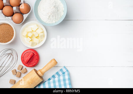 Weiße Holztisch Hintergrund mit backzutaten. Butter, Mehl, Eier, Zucker und Kochutensilien. Zutaten für Kekse backen, Kuchen, Teig pr Stockfoto