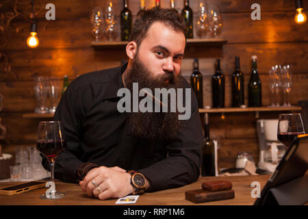 Hübscher junger Barkeeper spielen mit seinem Bart. Große Persönlichkeit. Stockfoto
