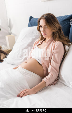 Müde schwangere Frau im Bett liegt und Kamera Stockfoto