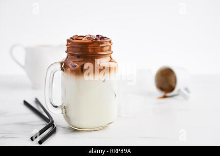 Eis Kaffee mit Milch in Mason jar und Black Metal Trinkhalme auf weißem Marmortisch mit weißem Hintergrund. Kopieren Sie Platz für Text. Stockfoto