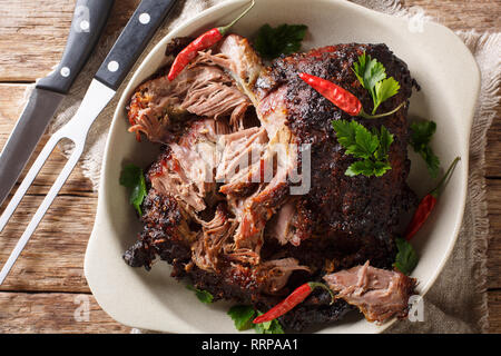 Langsam zog geschreddert Schweinefleisch close-up auf einem Schild auf dem Tisch gekocht. Horizontal oben Ansicht von oben Stockfoto