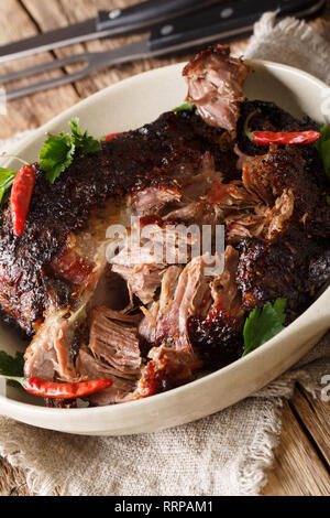 Langsam zog geschreddert Schweinefleisch close-up auf einem Schild auf dem Tisch gekocht. Vertikale Stockfoto