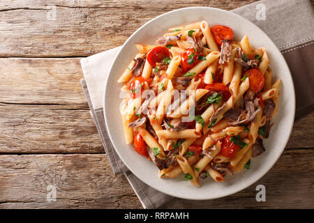 Mit Penne Pasta mit gezogen, Schweinefleisch, Käse, Tomatensauce und Kräuter close-up auf einem Teller auf den Tisch. horizontal oben Ansicht von oben Stockfoto