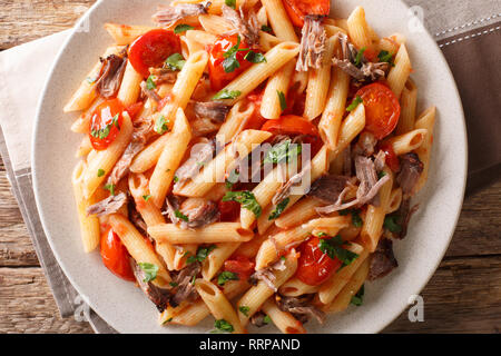 Italienische Pasta mit gebackenen zerfetzt, Schweinefleisch, Käse, Tomatensauce und Kräuter close-up auf einem Teller auf den Tisch. Horizontal oben Ansicht von oben Stockfoto