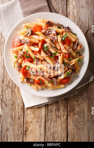 Mit Penne Pasta mit gezogen, Schweinefleisch, Käse, Tomatensauce und Kräuter close-up auf einem Teller auf den Tisch. Vertikal oben Ansicht von oben Stockfoto