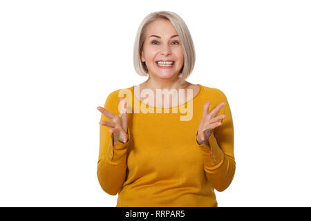 Attraktive Frau mittleren Alters lächelt emotional posiert im Studio auf weißem Hintergrund Stockfoto