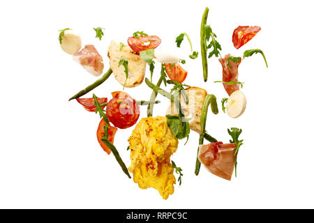 Fallende Gemüse isoliert. Scheiben Tomate, Eier, Spargel, Rucola, Salami, Schinken und Toast. Frischer Salat Zutaten in der Luft auf isolierte Stockfoto