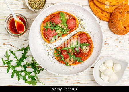 Hausgemachte Sandwiches mit Wurst, Mozzarella Käse, Ketchup und frische Rucola. Gourmet Brot Toast. Selektiver Fokus Stockfoto
