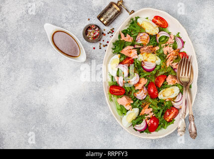 Frische Feinkost lachs Salat (Forellen) mit Salat, Tomaten, Eier und roten Zwiebeln mit Senf Dressing und Olivenöl in eine weiße Platte. Selektive f Stockfoto