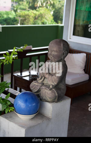 Kleine beten Buddha Statue Dekoration vor Thai Garden Patio Stockfoto