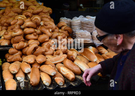 Eine ältere Frau geht an einer Brotbude am Yehuda-Markt in Jerusalem, Israel vorbei Stockfoto