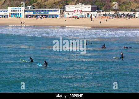 Bournemouth, Dorset, Großbritannien. 26 Feb, 2019. UK Wetter: warmes Wetter fährt mit einem anderen schönen warmen sonnigen Tag in Bournemouth wie Besucher die Sonne am Meer genießen, erwartet der heisseste Tag des Jahres zu sein und den heißesten Februar Tag überhaupt. Bournemouth strand ist der beste Strand in Großbritannien gewählt. Surfer im Wasser mit Menschen am Strand hinter. Credit: Carolyn Jenkins/Alamy leben Nachrichten Stockfoto