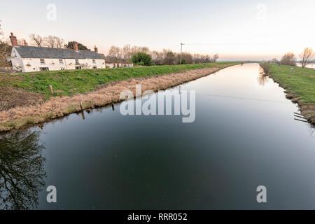 Sutton Gault, Cambridgeshire UK. 26. Februar 2019. Die New Bedford River ist komplett noch auf einer windstillen Abend nach einem ungewöhnlich warmen Tag im Februar, wo Temperaturen erreicht die hohen Teens Celsius über viel von Großbritannien. Die flache, freiliegenden Moorlandzone Landschaft in der Regel windig und kalt diese Zeit des Jahres werden aber die Unseasonal warmes Wetter hat zu einem ruhigen Abend geführt. Credit: Julian Eales/Alamy leben Nachrichten Stockfoto