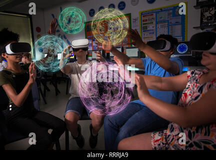 Junior high school Kursteilnehmer mit Virtual Reality Simulatoren in dunklen Klassenzimmer Stockfoto