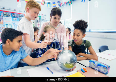 Neugierig Junior High School Studenten Sie suchen bei Globe im Klassenzimmer Stockfoto