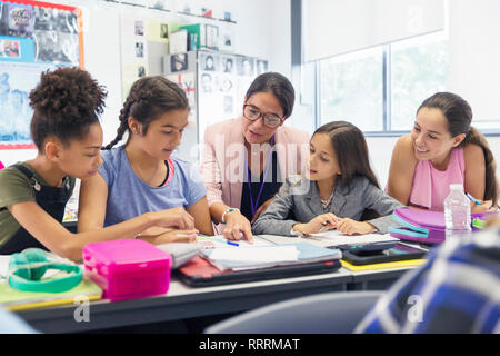 Lehrerin und Junior high school girl Studierende an der Schreibtisch im Klassenzimmer Stockfoto